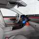 the interior of the 2023 mercedes-amg s 63 e performance sedan, as seen from the passenger seat. the upholstery is dove gray, and orange accent lighting emanates from the dashboard and driver's door